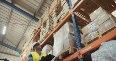 Düşük açılı izleme atış büyük bir depoda yürüyen bir lojistik işçinin