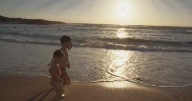 Üç çalışan ve birlikte sahilde günbatımı sırasında oynayan çocuklar