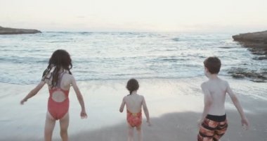 Üç çalışan ve birlikte sahilde günbatımı sırasında oynayan çocuklar