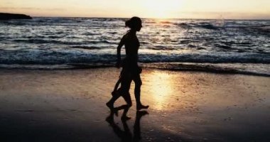 Anne ve kızı kumsalda günbatımında çalışan