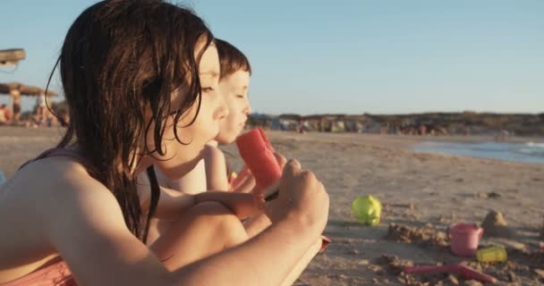 Tre bambini che mangiano angurie in spiaggia durante il tramonto — Video Stock