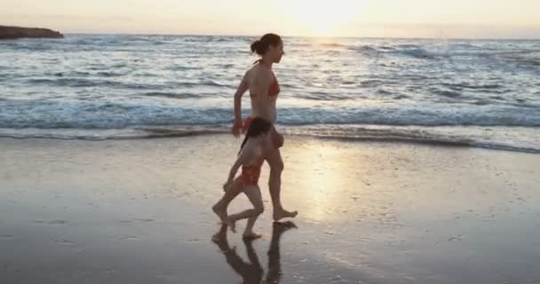 Матері та її дочка працює на пляжі на заході сонця — стокове відео