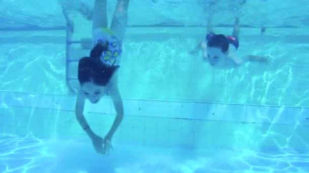 Unterwasseraufnahmen von zwei Kindern, die in einem Schwimmbad springen und tauchen — Stockvideo