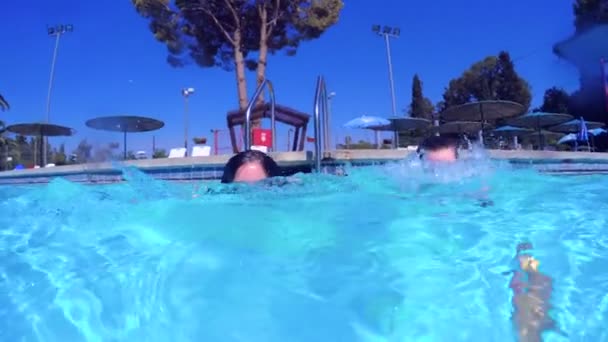 Tiro subaquático de duas crianças pulando e mergulhando em uma piscina — Vídeo de Stock