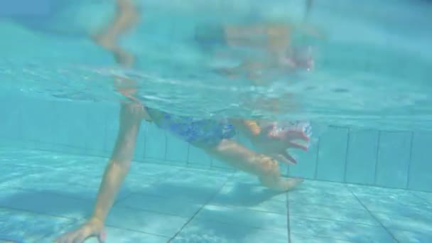 Unterwasseraufnahmen eines kleinen Mädchens beim Spielen und Springen in einem Schwimmbad — Stockvideo