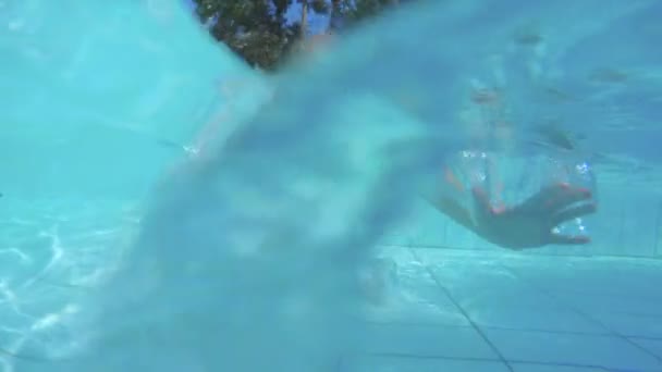 Filmagem subaquática de uma menina brincando e pulando em uma piscina — Vídeo de Stock