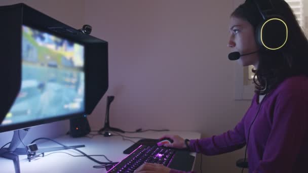 Tiener meisje zitten in de voorkant van een computer, het spelen van een spel met een headset — Stockvideo