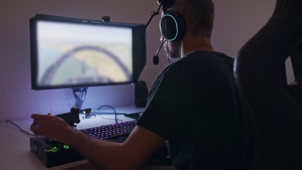 Hombre jugando un simulador de vuelo en el ordenador, usando un auricular — Vídeos de Stock