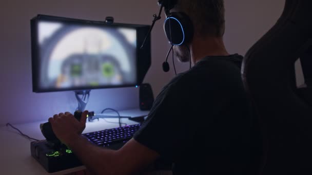 Hombre jugando un simulador de vuelo en el ordenador, usando un auricular — Vídeos de Stock