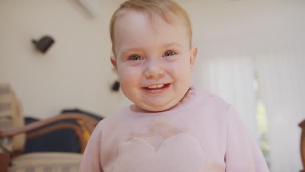 Милая девочка, играющая дома и улыбающаяся в камеру — стоковое видео