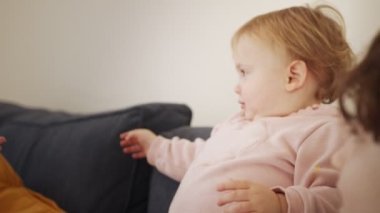 Küçük kız iki genç kızla oynuyor, gülüyor ve gülümsüyor.