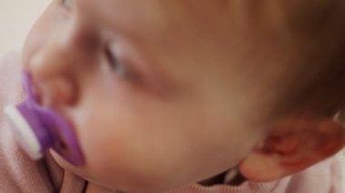 Evde ağzında emziğiyle oynayan tatlı bir kız çocuğu.