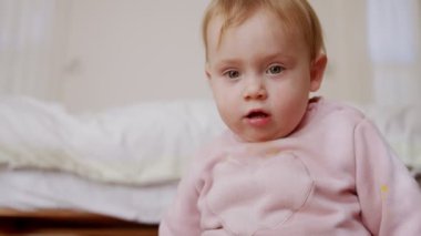 Evde oynayan sevimli bir bebek ve kameraya gülümsüyor.