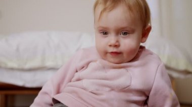 Evde oynayan sevimli bir bebek ve kameraya gülümsüyor.