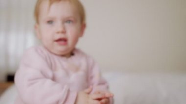 Tatlı bebek yatakta oturuyor, oynuyor, yuvarlanıyor ve gülüyor.