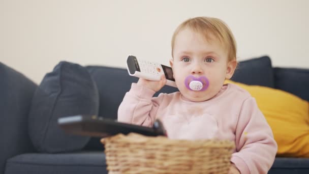 Lindo bebé jugando con un control remoto un teléfono — Vídeo de stock