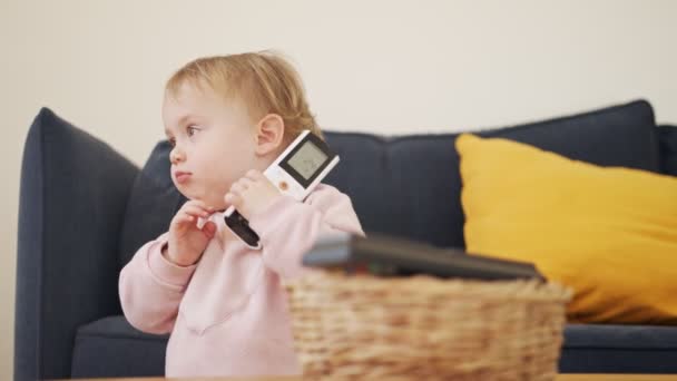 Cute baby playing with a remote control a telephone — Stock Video