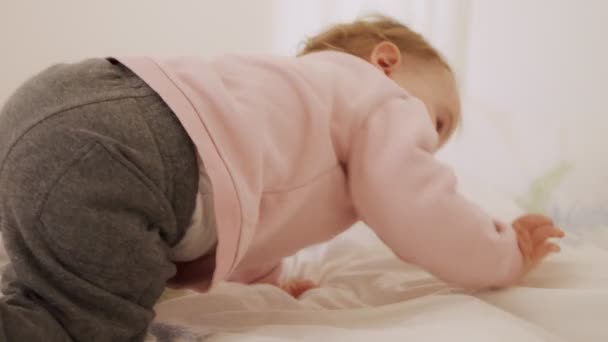 Cute baby girl sitting on a bed, playing, rolling and laughing — Stock Video