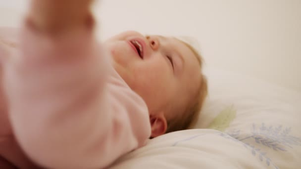 Cute baby girl sitting on a bed, playing, rolling and laughing — Stock Video