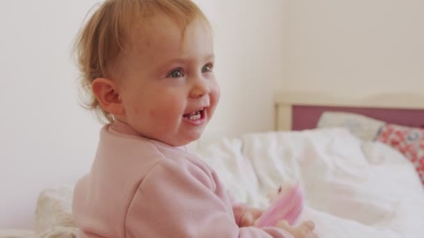 Cute baby sitting on a bed, playing, rolling and laughing — Stock Video
