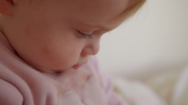 Lindo bebé sentado en una cama, jugando, rodando y riendo — Vídeos de Stock
