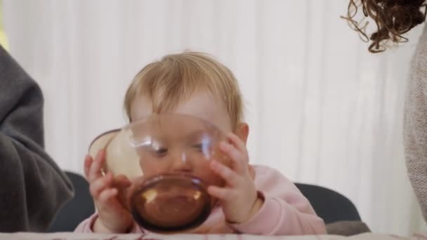 Niedliches Baby isst eine Orange aus einer Glasschüssel — Stockvideo