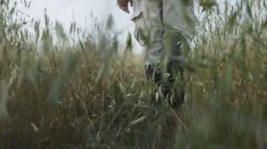 Yüksek çizmeler giyen bir adamın yoğun bitki örtüsünde yürümesi.