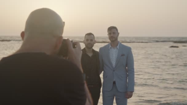 Photographer taking pictures of gay couple before their wedding on the beach — Stock Video