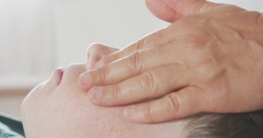 Shiatsu tedavisi. Masöz, genç bir çocuğa nazik bir yüz masajı yapıyor.
