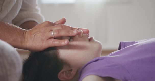 Лечение шиацу. Массажистка нежно обращается с лицом маленькой девочки — стоковое видео