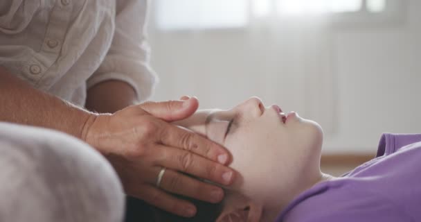 Shiatsu treatment. Masseuse giving gentle face treatment to a little girl — Vídeos de Stock