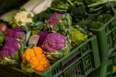 Colorful cauliflower variety displayed in green crates at market.