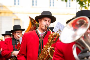 Klagenfurt, Austria - October 04, 2025: Musicians dressed in red perform with saxophones at Erntedankfest in Benediktinermarkt, creating a lively atmosphere