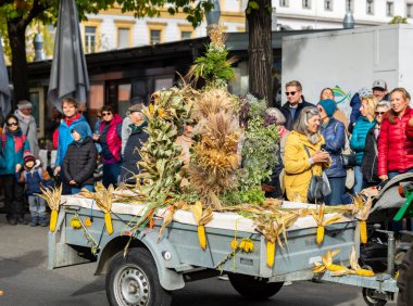 Klagenfurt, Austria - October 04, 2025: Vibrant Erntedankfest scene in Benediktinermarkt featuring a decorated trailer and cheerful crowd celebrating together