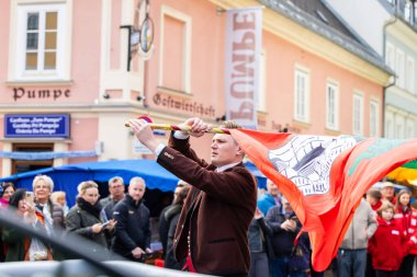 Klagenfurt, Austria - October 04, 2025: Young man is waving flag at Erntedankfest in Benediktinermarkt, with vibrant crowd and festive atmosphere