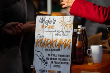 Klagenfurt, Austria - October 04, 2025: Maja's Bio Shots stand features fresh turmeric and ginger at Erntedankfest in Benediktinermarkt, inviting visitors to taste local flavors