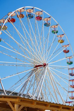 Colorful ferris wheel against clear blue sky in daylight.