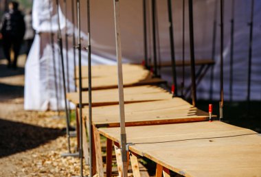 Empty market stalls with wooden tables and white tent outdoors.