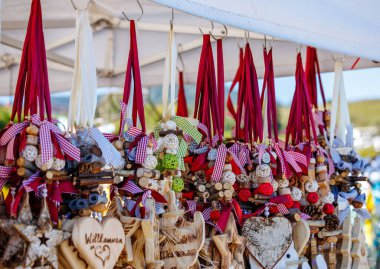 Colorful handmade wooden decorations with red ribbons at outdoor market display.