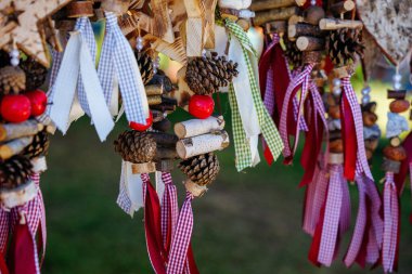 Rustic hanging decorations with pine cones and ribbons outdoors.