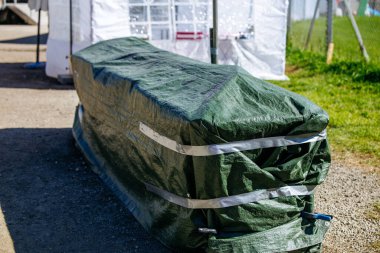 Güneşli bir günde çadırın yanında yeşil muşamba kaplı bir nesne..