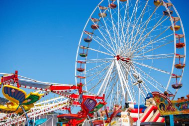 St Veit An Der Glan, Austria - October 03, 2025: Vibrant amusement park scene at St. Veiter Wiesenmarkt featuring a large Ferris wheel and thrilling rides