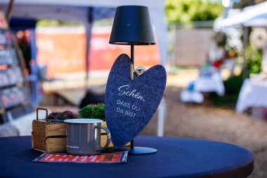 St Veit An Der Glan, Austria - October 03, 2025: Heart-shaped sign with welcoming text on table at St. Veiter Wiesenmarkt, showcasing festive decorations and lively ambiance