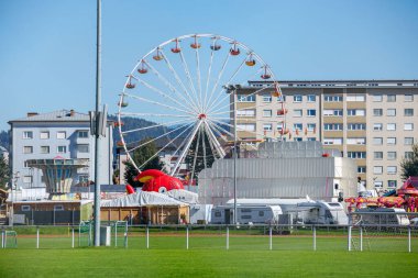 St Veit An Der Glan, Austria - October 03, 2025: St. Veiter Wiesenmarkt showcases a lively fairground with a Ferris wheel, amusement rides, and nearby buildings