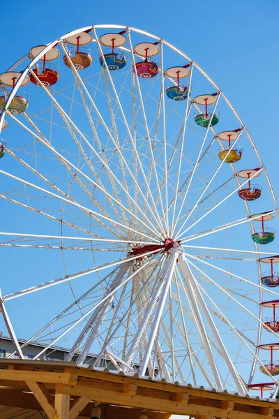 Colorful ferris wheel against clear blue sky in daylight.