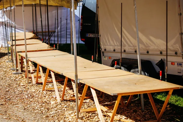 St Veit An Der Glan, Austria - October 03, 2025: Wooden tables arranged for St. Veiter Wiesenmarkt, with tents and fallen leaves enhancing the lively outdoor setting