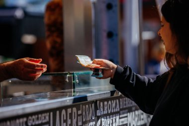 St Veit An Der Glan, Austria - October 03, 2025: Young woman is exchanging cash with vendor at St. Veiter Wiesenmarkt, capturing lively food stall experience