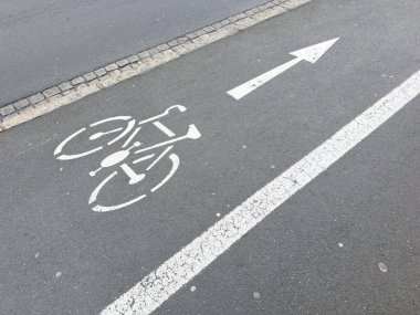 Bicycle lane marking on urban road with directional arrow.