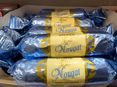 Villach, Austria - October 09, 2025: Stacked nougat bars in blue wrapping from Vitana, featuring a chocolate coating and appealing presentation for sweet enthusiasts