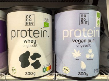 Villach, Austria - October 09, 2025: Protein powder packaging displayed in store, featuring whey and vegan varieties, promoting fitness and health-conscious diets